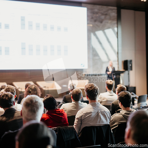 Image of Female speaker giving a talk on corporate business conference. Unrecognizable people in audience at conference hall. Business and Entrepreneurship event.