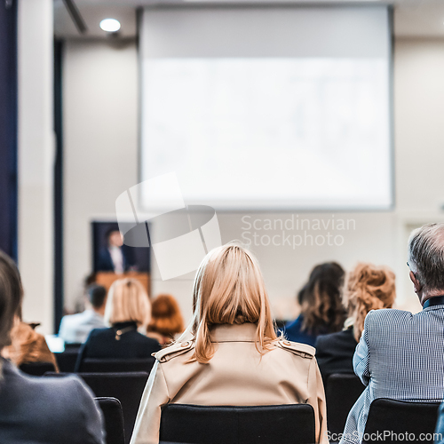 Image of Speaker giving a talk in conference hall at business event. Rear view of unrecognizable people in audience at the conference hall. Business and entrepreneurship concept.