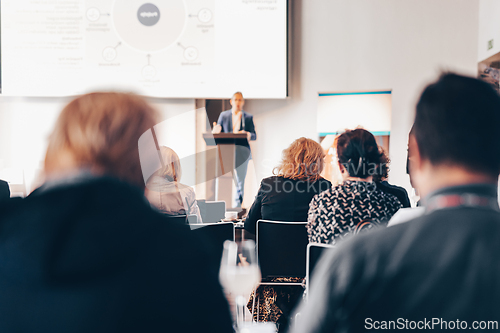 Image of Speaker giving a talk in conference hall at business event. Rear view of unrecognizable people in audience at the conference hall. Business and entrepreneurship concept.