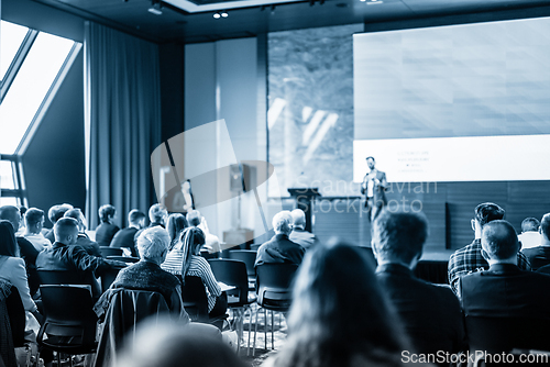 Image of Speaker giving a talk in conference hall at business event. Business and entrepreneurship concept. Blue toned black and white image.