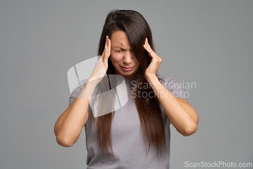 Image of Stressed woman pressing temples during intense headache attack, eyes closed
