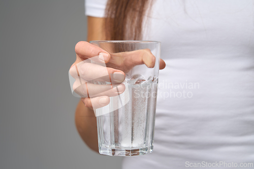 Image of Close-up of woman holding glass of water with dissolving vitamin tablets