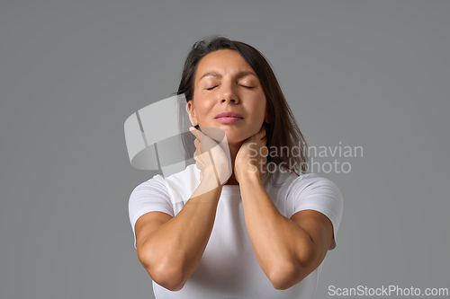 Image of Calm woman closing eyes and holding neck gently expressing relief and relaxation