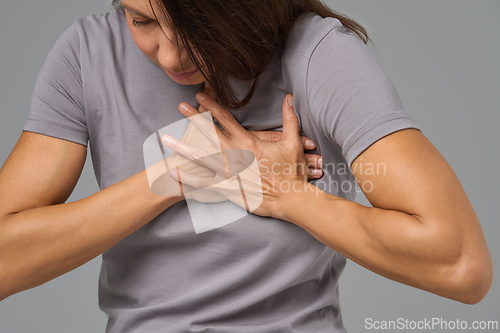 Image of Close-up of woman clutching chest in pain, eyes closed, expressing discomfort