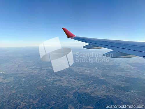 Image of wing of an airplane flying high above the ground