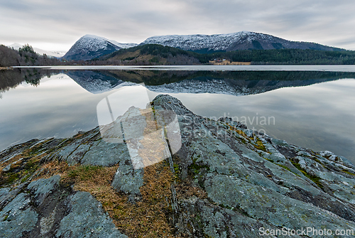 Image of Calm reflections on a tranquil lake surrounded by majestic mount