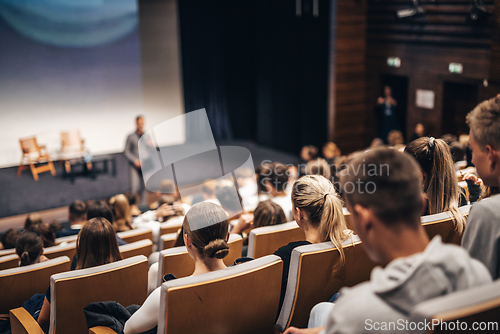 Image of Speaker giving a talk in conference hall at business event. Rear view of unrecognizable people in audience at the conference hall. Business and entrepreneurship concept.