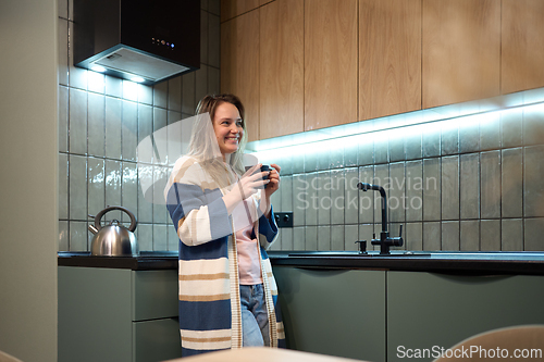 Image of Freelancer evening routine with warm drink in modern kitchen
