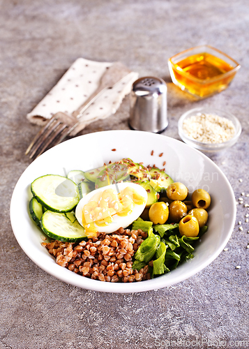 Image of Bowl of tasty buckwheat porridge and egg on table