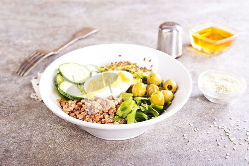 Image of Bowl of tasty buckwheat porridge and egg on table