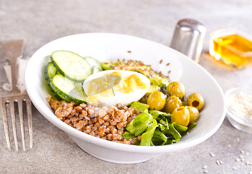Image of Bowl of tasty buckwheat porridge and egg on table