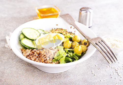 Image of Bowl of tasty buckwheat porridge and egg on table