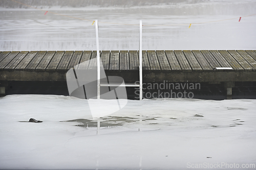 Image of wooden pier and ladder on the lake in winter