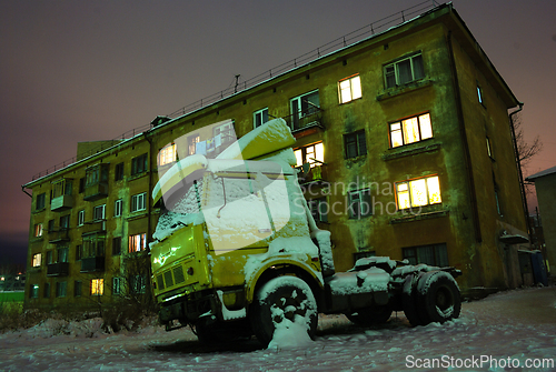 Image of old truck parked near a concrete building at night 