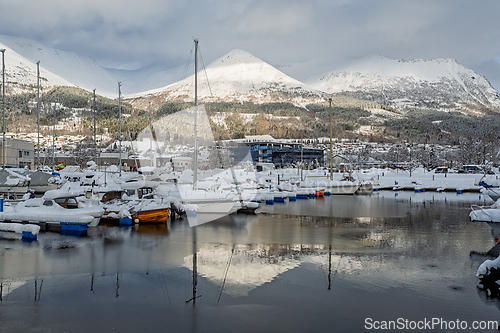 Image of Snow-covered boats rest peacefully in a serene harbor overlooked