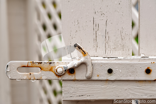 Image of Rusty latch on a weathered white gate brings a sense of rustic c