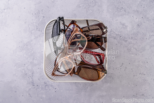 Image of Assortment of used eyeglasses and sunglasses in a basket, concept of recycling