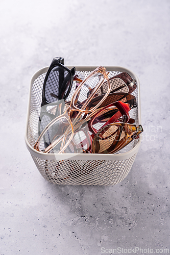 Image of Assortment of used eyeglasses and sunglasses in a basket, concept of recycling