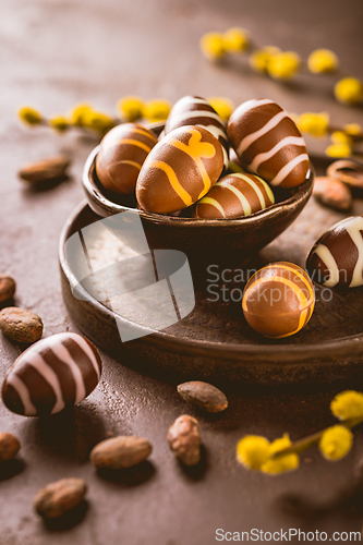 Image of Sweet chocolate eggs with cocoa beans in brown tone for Easter