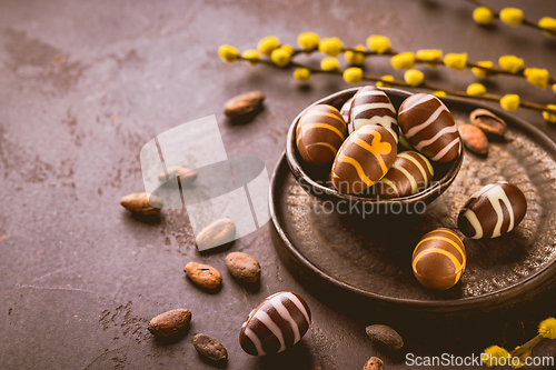 Image of Sweet chocolate eggs with cocoa beans in brown tone for Easter
