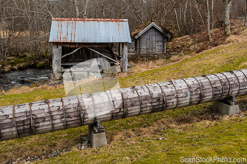 Image of Old wooden structures stand resilient beside a flowing stream un