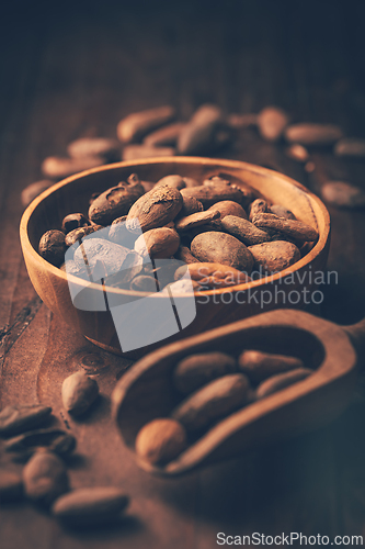 Image of Organic cocoa beans in wooden bowl on kitchen table