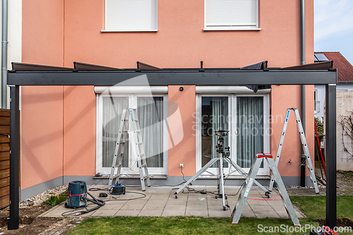 Image of Workers install patio roofing with steel and glass