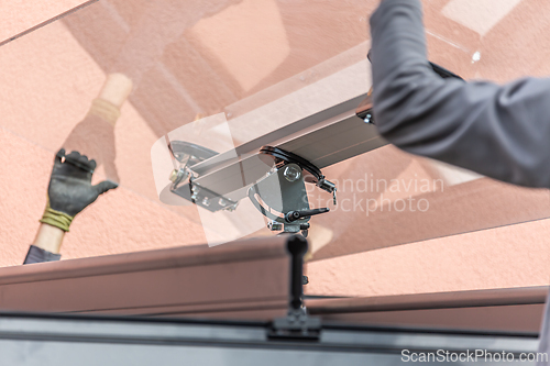 Image of Workers install patio roofing with steel and glass