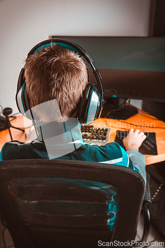 Image of Teenager in headphones playing video game on his computer