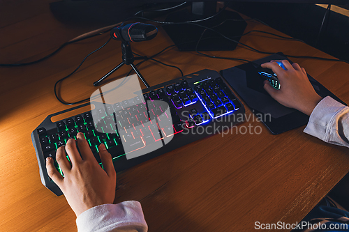 Image of Detail of hand on keyboard, playing video game on computer