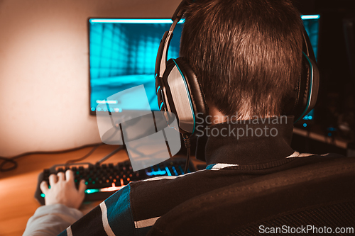 Image of Teenager in headphones playing video game on his computer