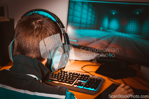 Image of Teenager in headphones playing video game on his computer