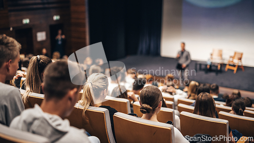 Image of Speaker giving a talk in conference hall at business event. Rear view of unrecognizable people in audience at the conference hall. Business and entrepreneurship concept.