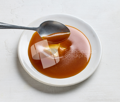 Image of plate of homemade soft caramel sauce on white table background
