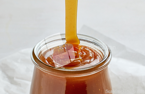 Image of freshly cooked homemade caramel sauce pouring in jar