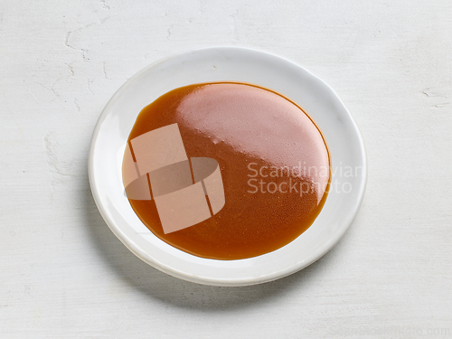 Image of plate of homemade soft caramel sauce on white table background
