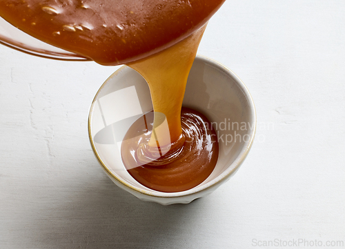 Image of freshly cooked caramel sauce pouring in bowl