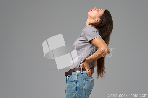 Image of Woman arching back with hands on waist in discomfort, looking upward,