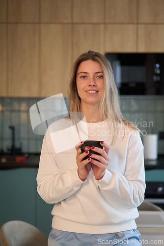 Image of Woman Holding a Warm Cup in a Softly Lit Kitchen