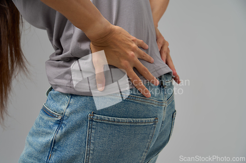 Image of Close-up of person holding lower back in pain, showing discomfort