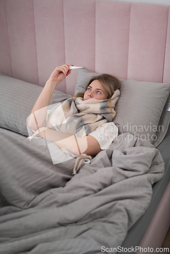 Image of Sick Morning Wrapped in Blanket While Checking Temperature