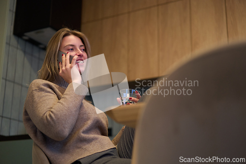 Image of Smiling During a Phone Call in a Warm Kitchen Setting