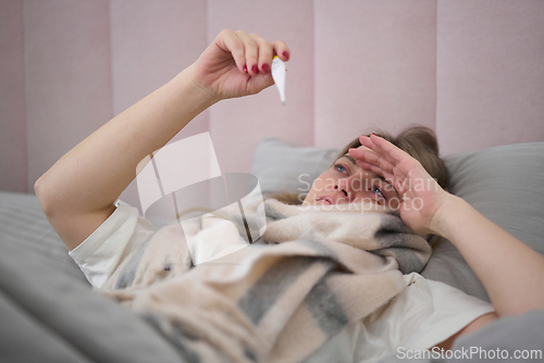 Image of Checking Temperature While Resting Under Warm Blanket
