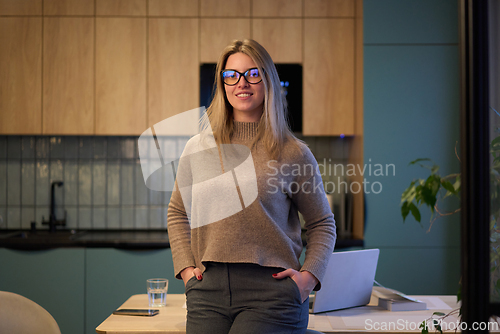 Image of Confident Woman Standing in a Warm Modern Kitchen
