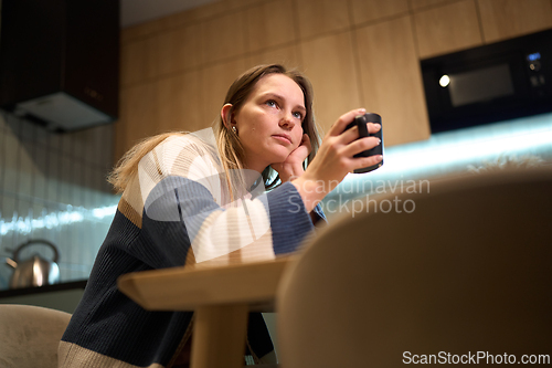 Image of Young Woman Drinking Coffee Alone in Quiet Kitchen Moment