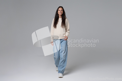 Image of Full length of happy woman walking towards camera on grey background smiling