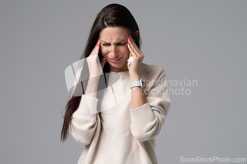 Image of Woman suffering from severe headache holding hands to temples isolated on grey background