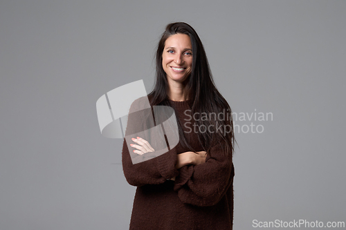 Image of Smiling woman standing with crossed arms looking at camera isolated on grey background