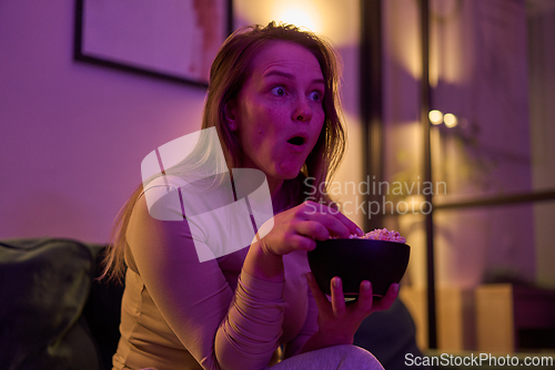 Image of Female reacting with popcorn bowl while watching screen at home