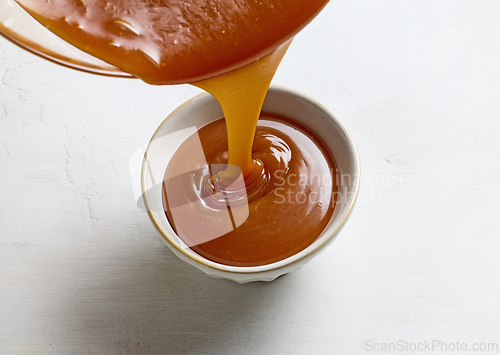 Image of freshly cooked caramel sauce pouring in bowl